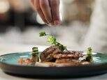 A chef garnishing a plated dish