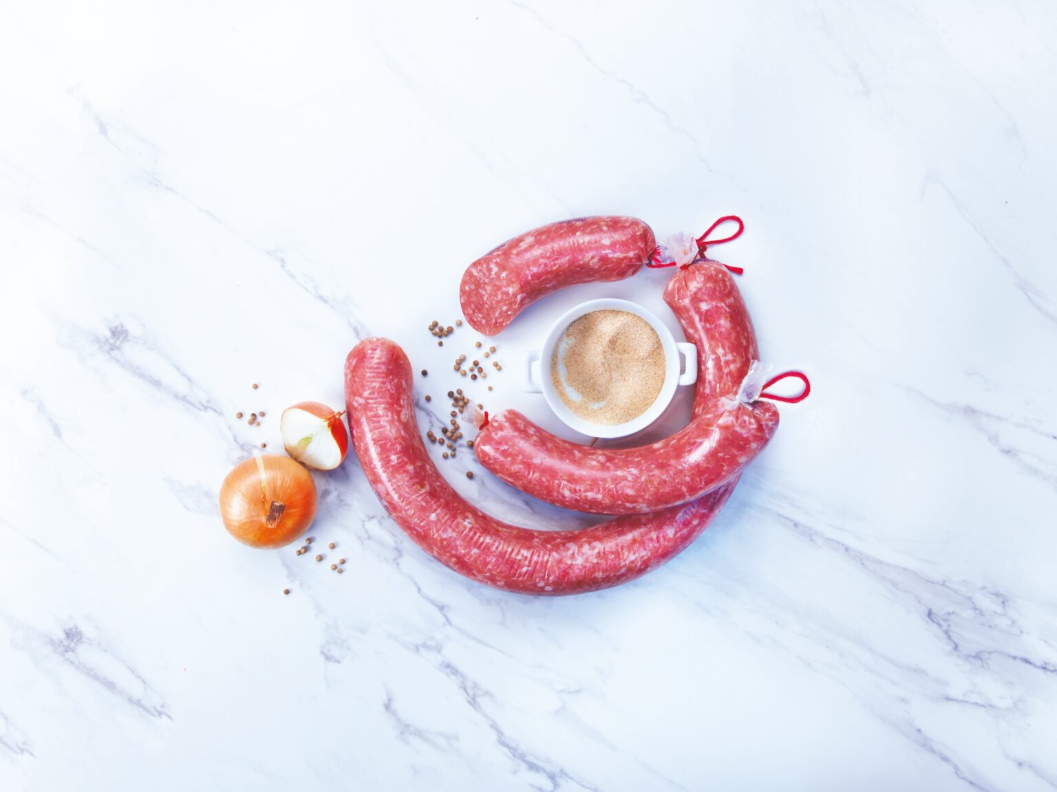 Sausages with an onion and a bowl of seasoning