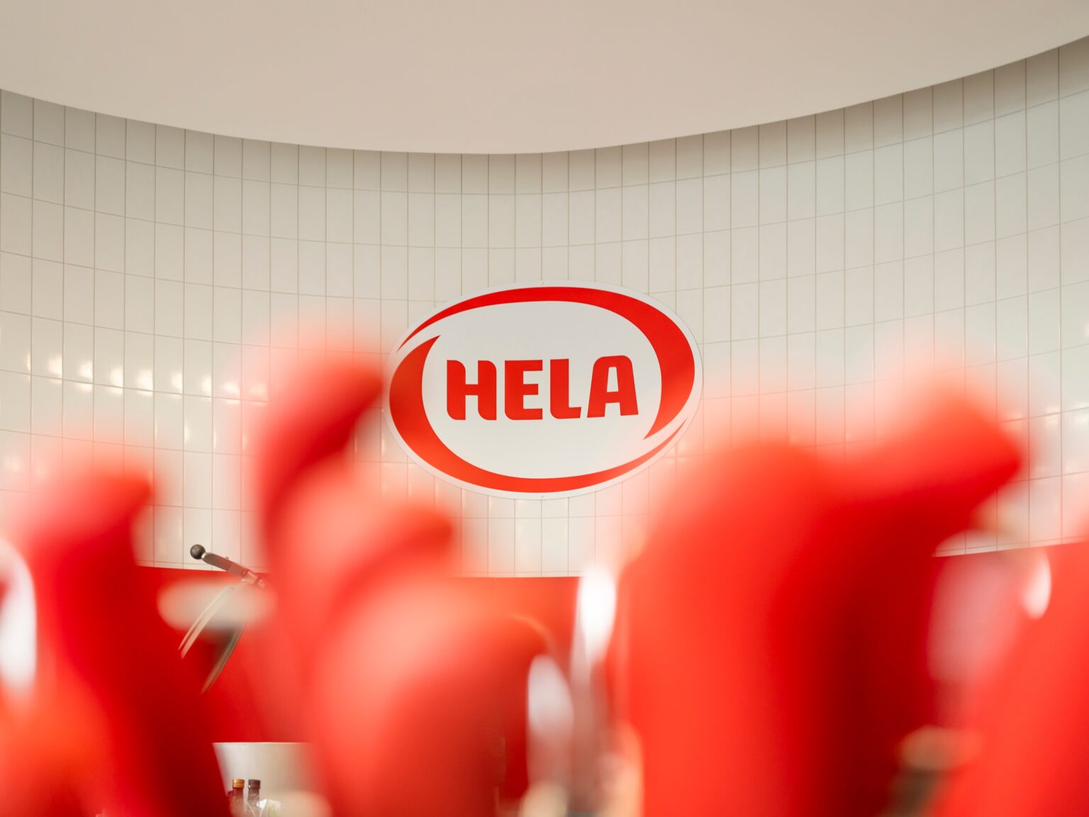 HELA logo with red product bottles in the foreground