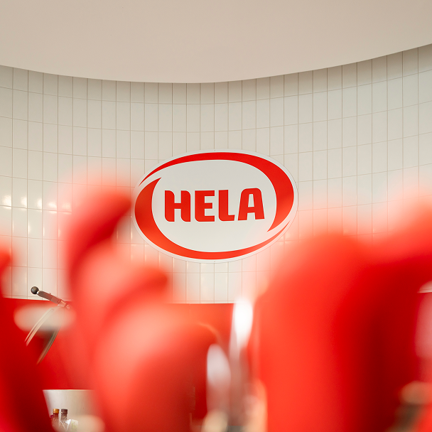 HELA logo on a wall behind red out-of-focus shapes