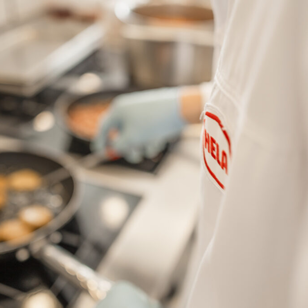 A cook in a HELA jacket at the stove