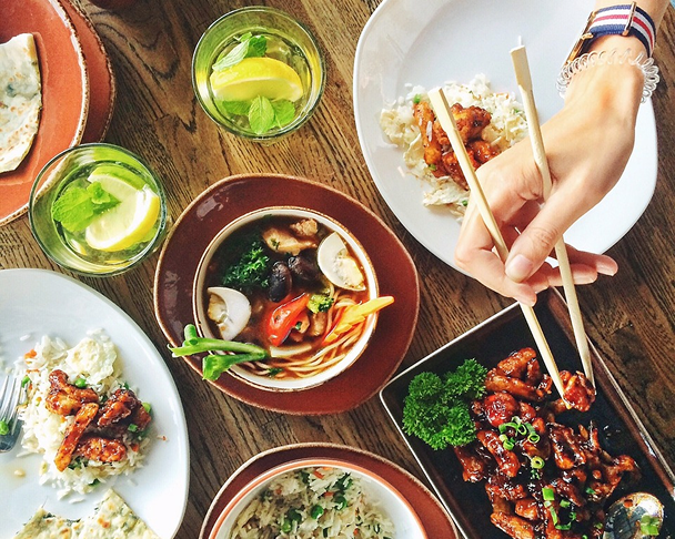 Asian dishes on a wooden table, eaten with chopsticks