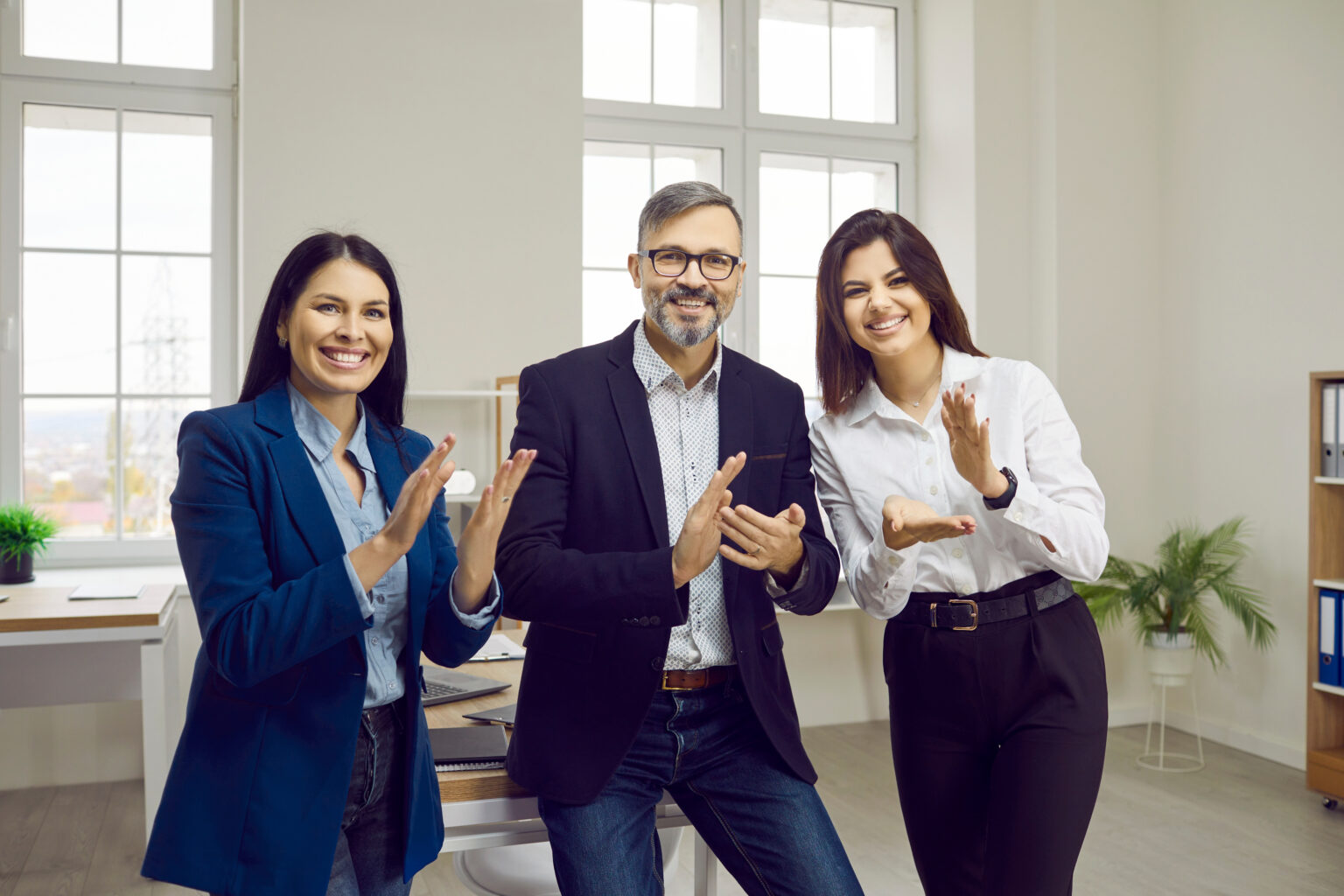 Three colleagues applauding in an office