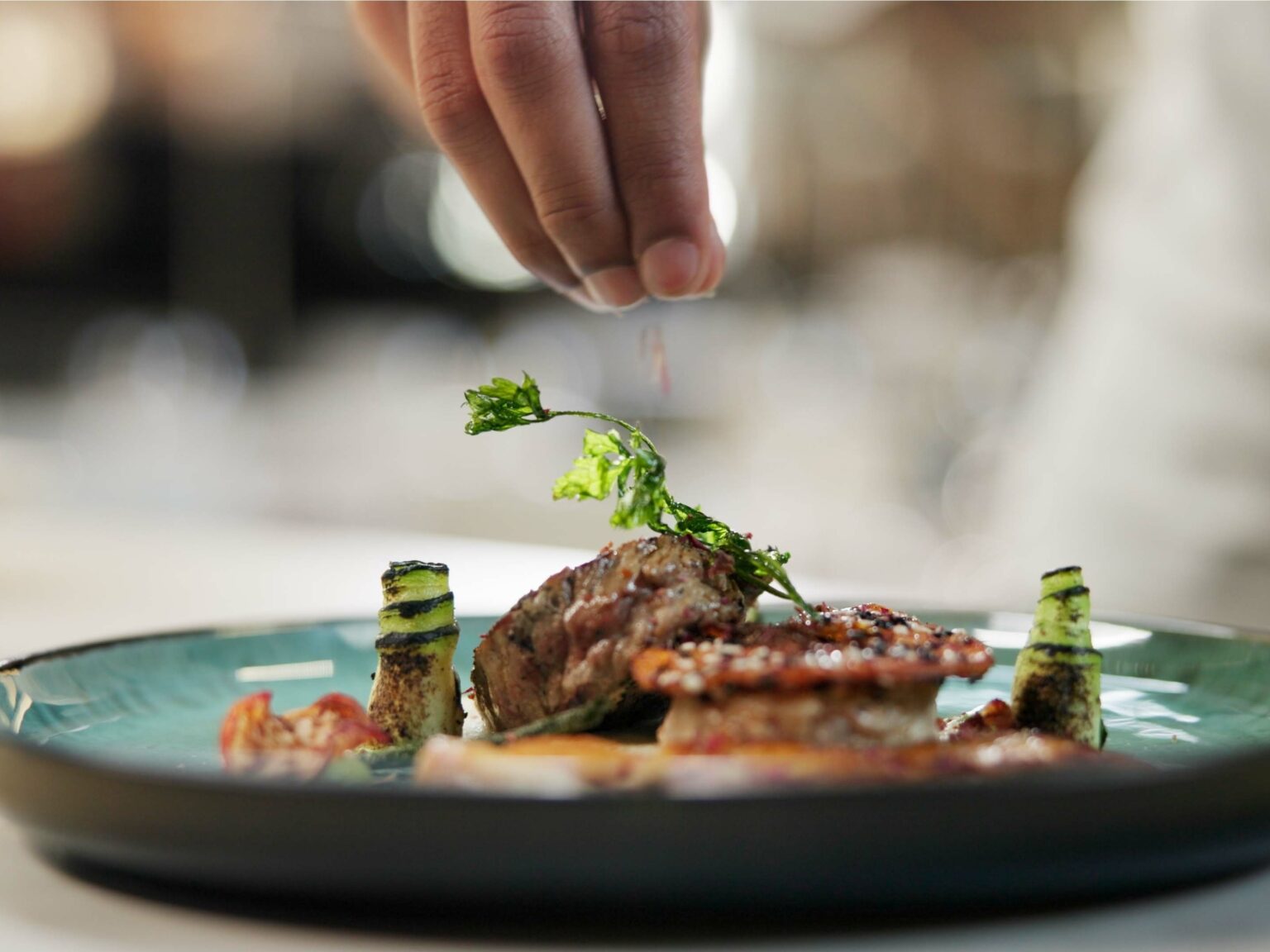 A chef garnishing a plated dish