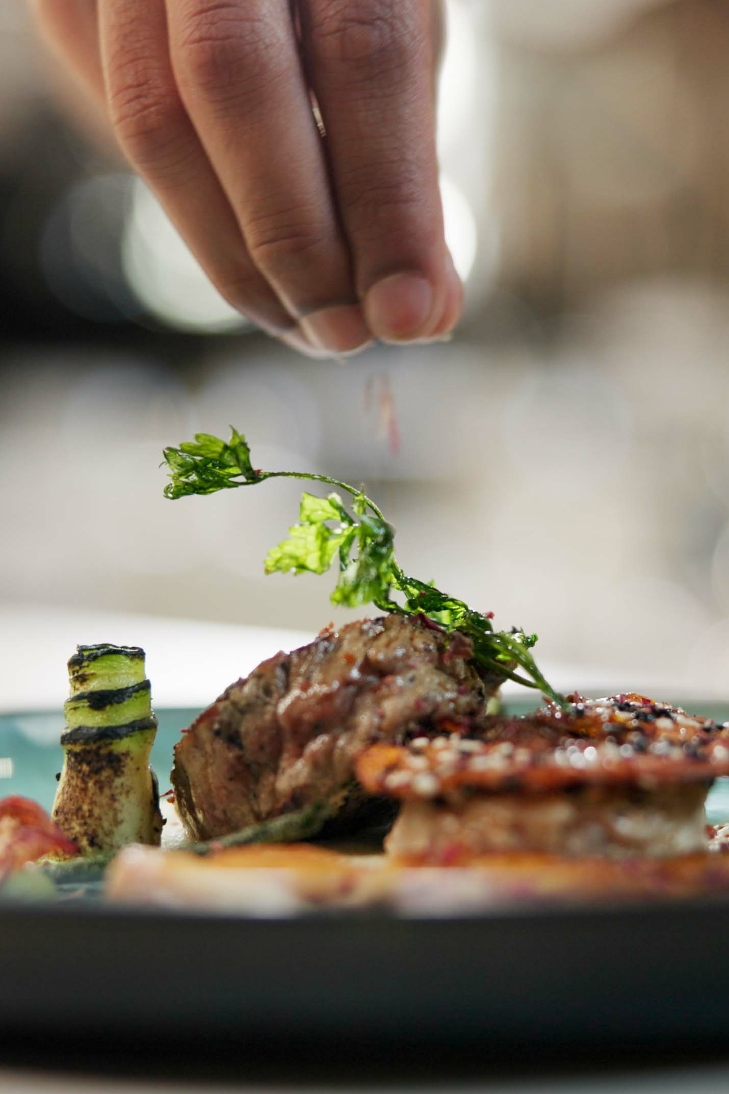 A chef garnishing a plated dish