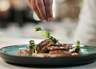 A chef garnishing a plated dish