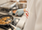 A cook wearing a HELA jacket in a kitchen