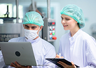 Food production staff reviewing information on a laptop