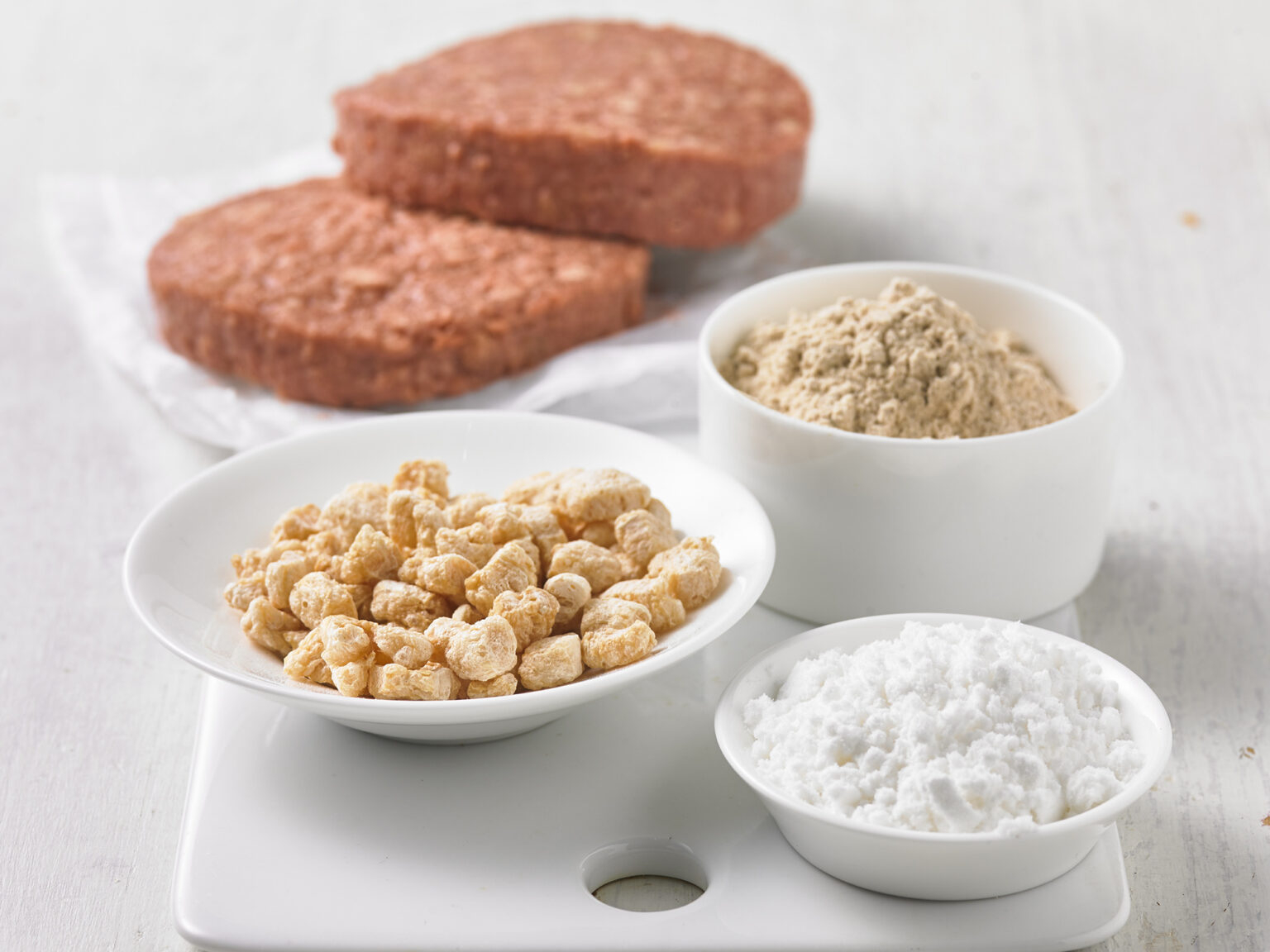Plant-based patties with ingredients in bowls